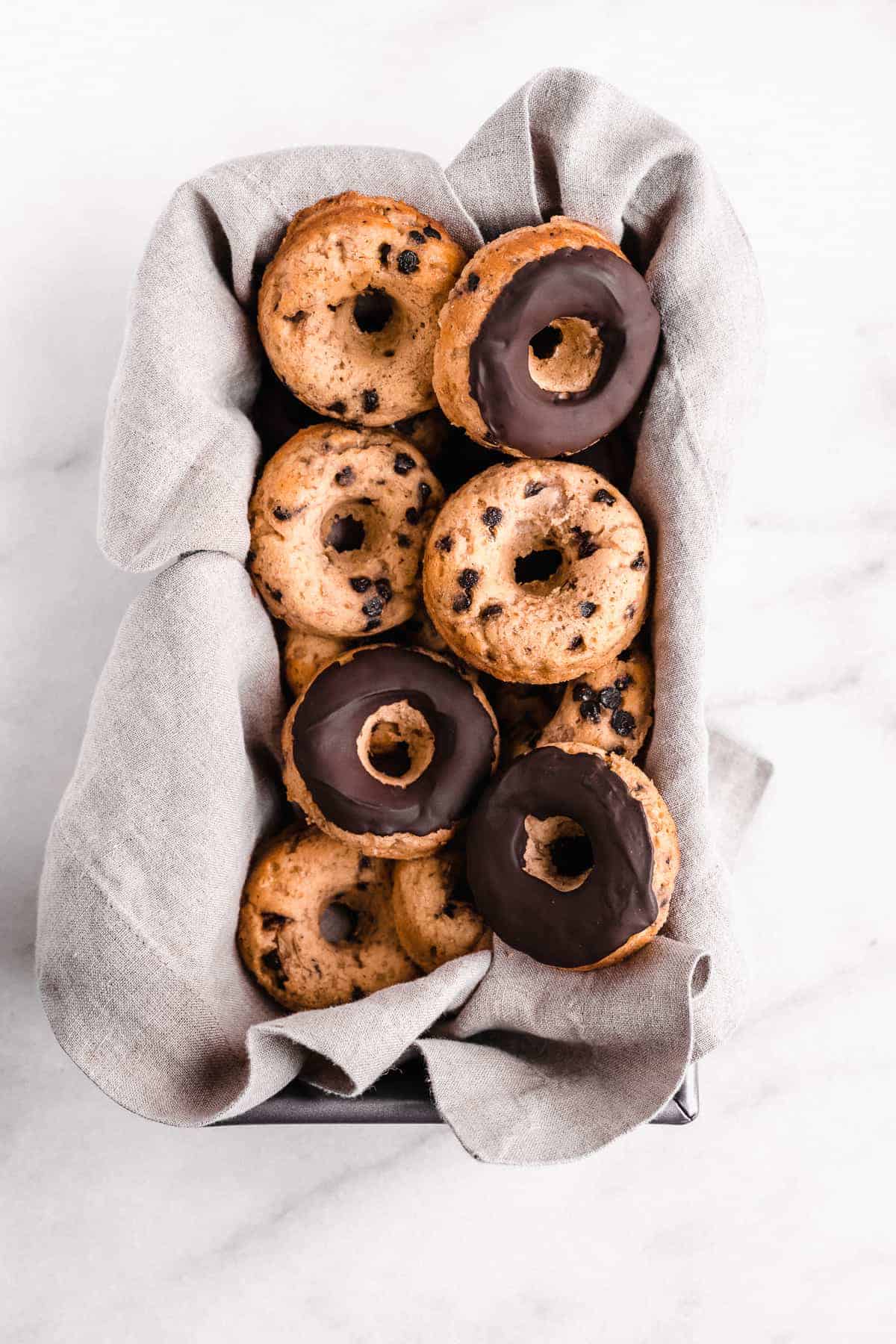 Banana Bread Doughnuts mounded in a rectangular baking dish laying on a gray linen cloth.