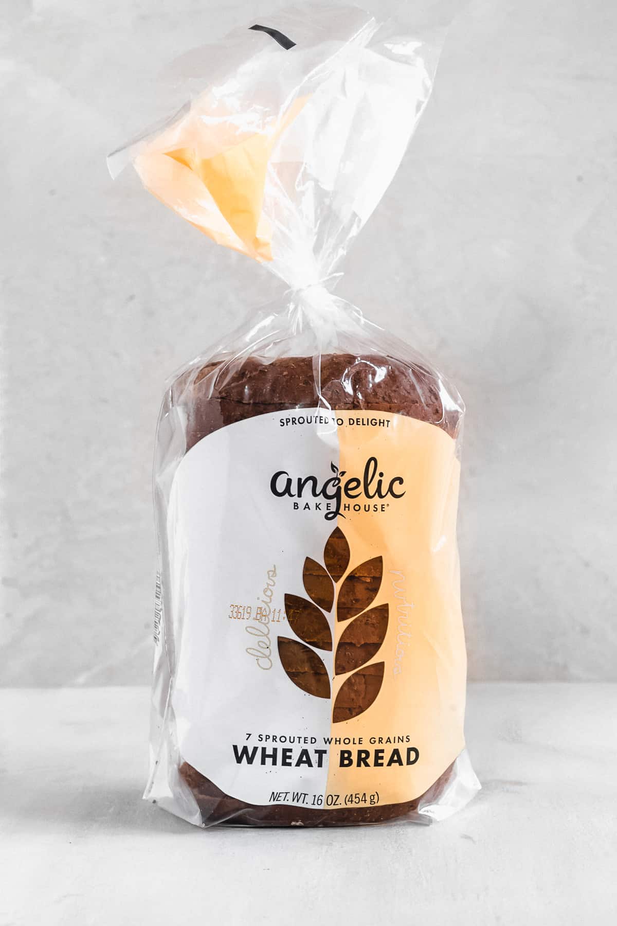Side view photo of a loaf of Angelic Bakehouse Wheat Bread sitting on a white marble slab.  