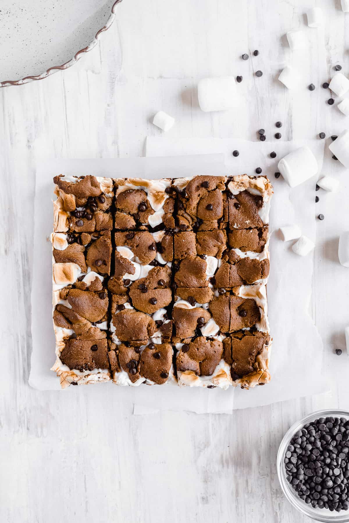 Baked s'more bars on a white sheet sliced into squares.
