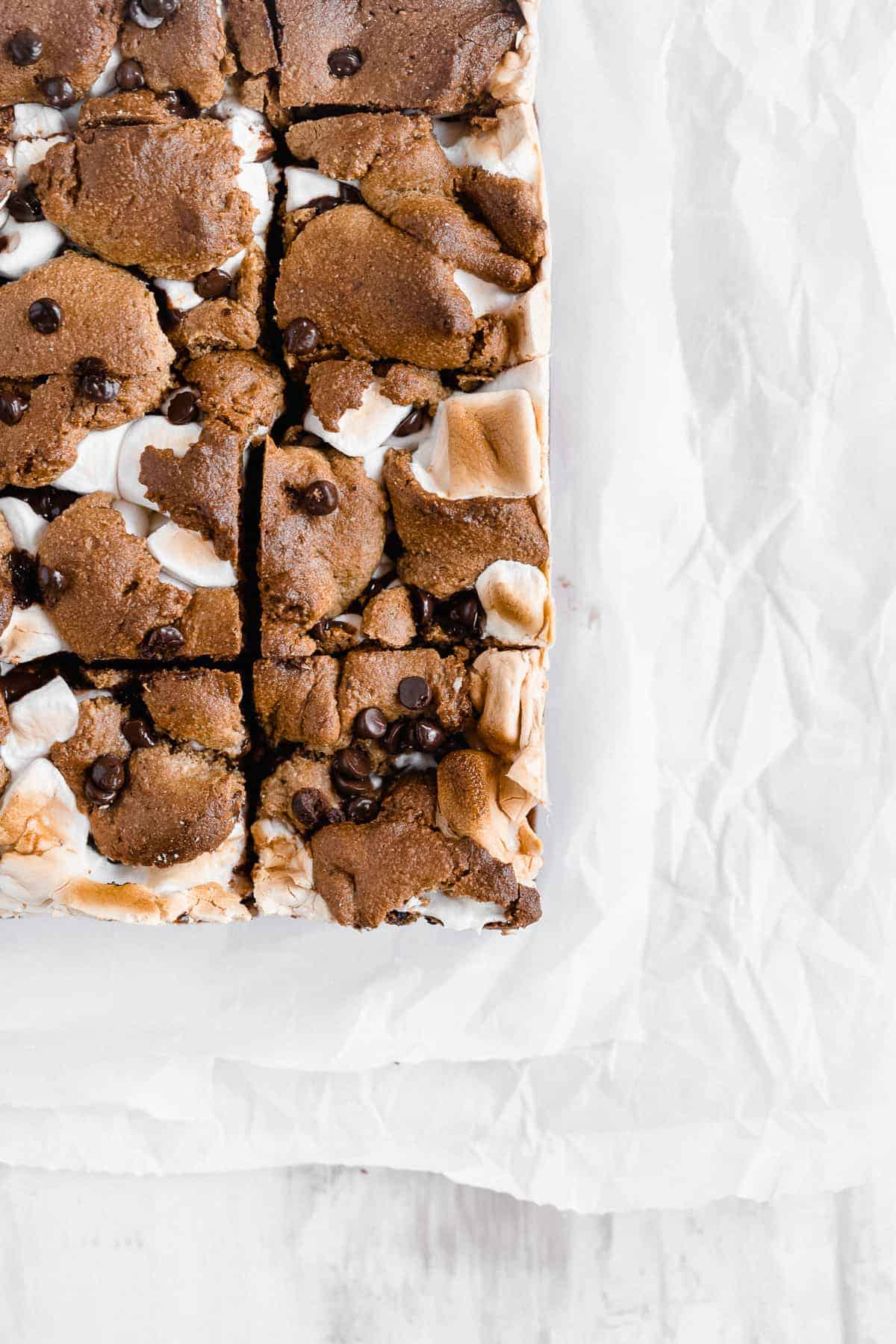 Corner of s'mores bars on a white parchment paper.