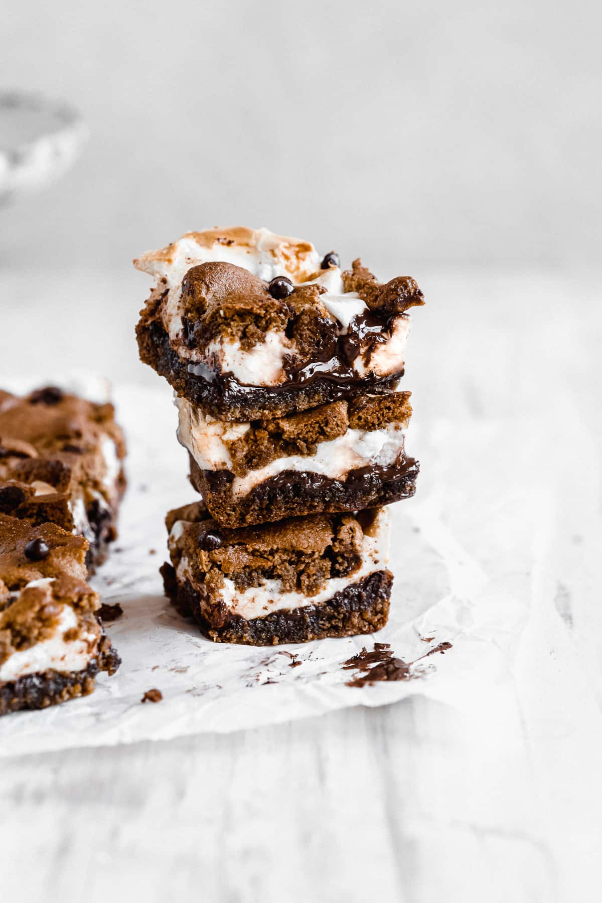 Three stacked s'mores bars with melted chocolate on white background.