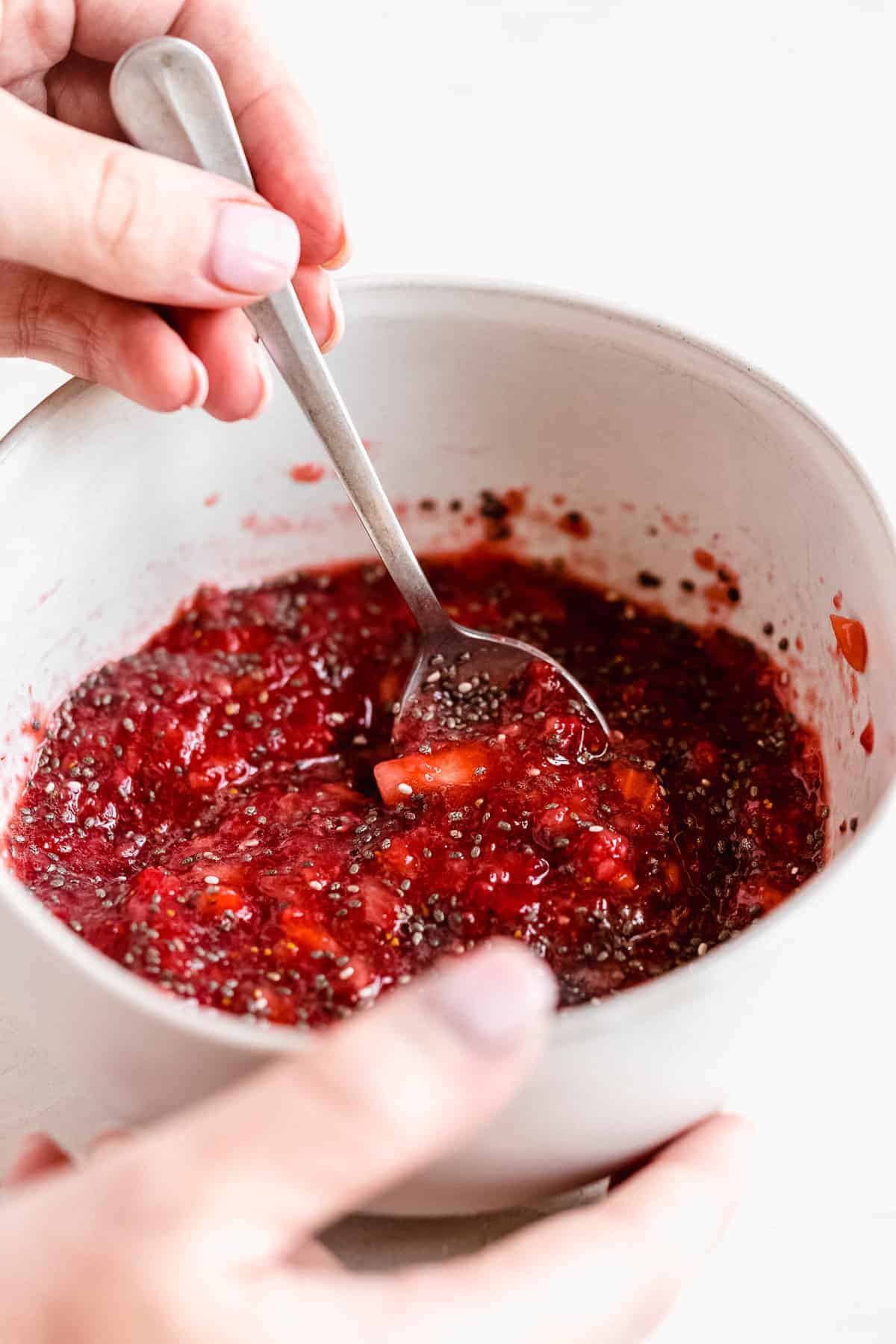 Process photo of the strawberry filling being mixed in a small white bowl with a spoon.