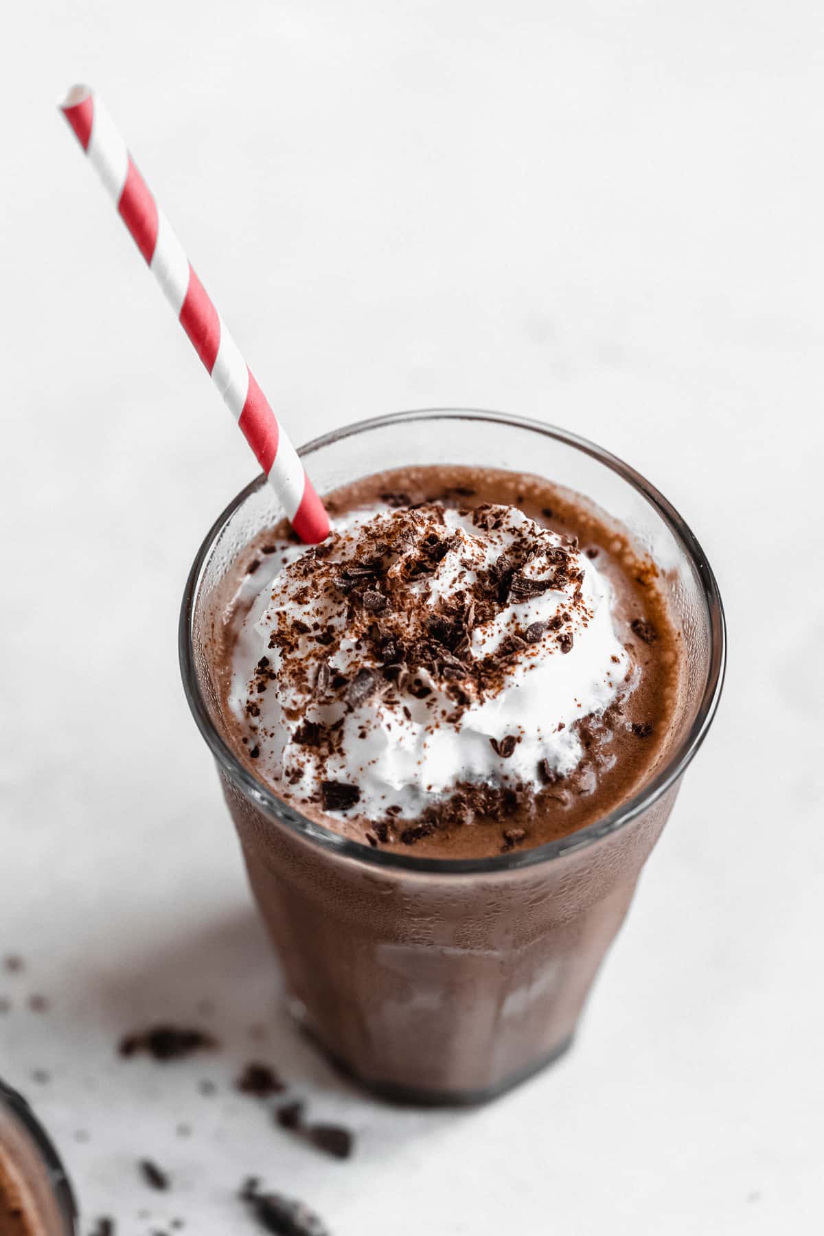 Overhead image of a glass of Frozen Mexican Hot Chocolate  with a red and white striped straw poking out of the glass.  