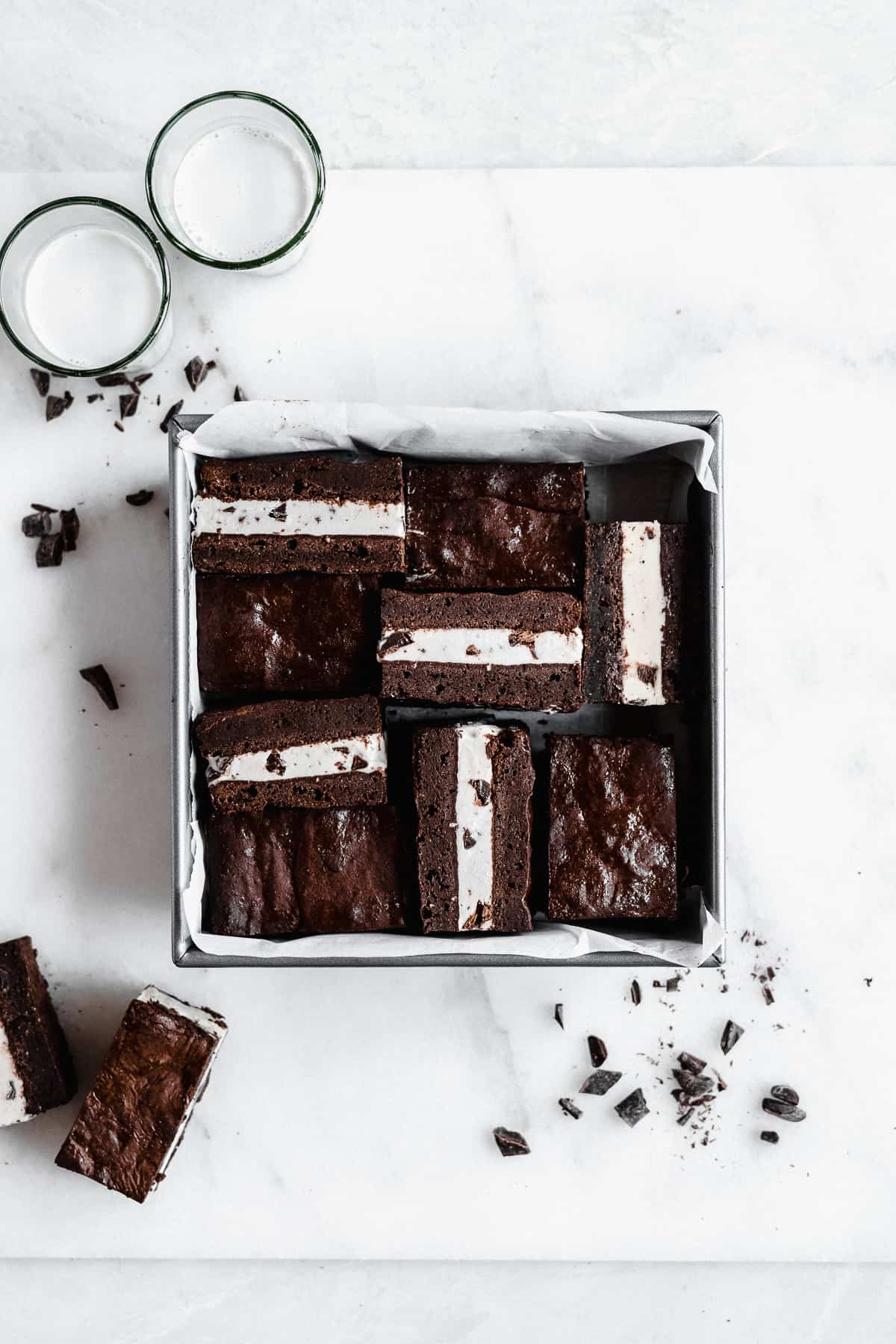 Overhead photo of a square metal baking pan that was used to house the Brownie Ice Cream Sandwiches while they froze. The Brownie Ice Cream Sandwiches have been cut into squares.