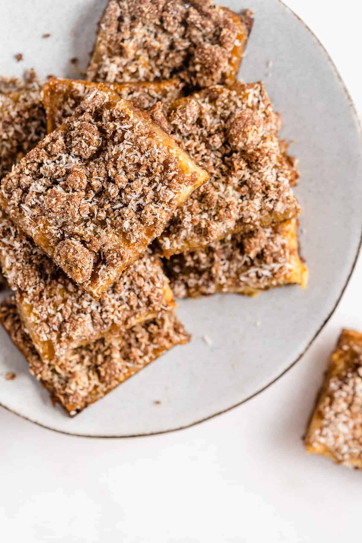 Overhead photo of several Pineapple Coconut Crumb Bars mounded on top of one another on a gray plate.  