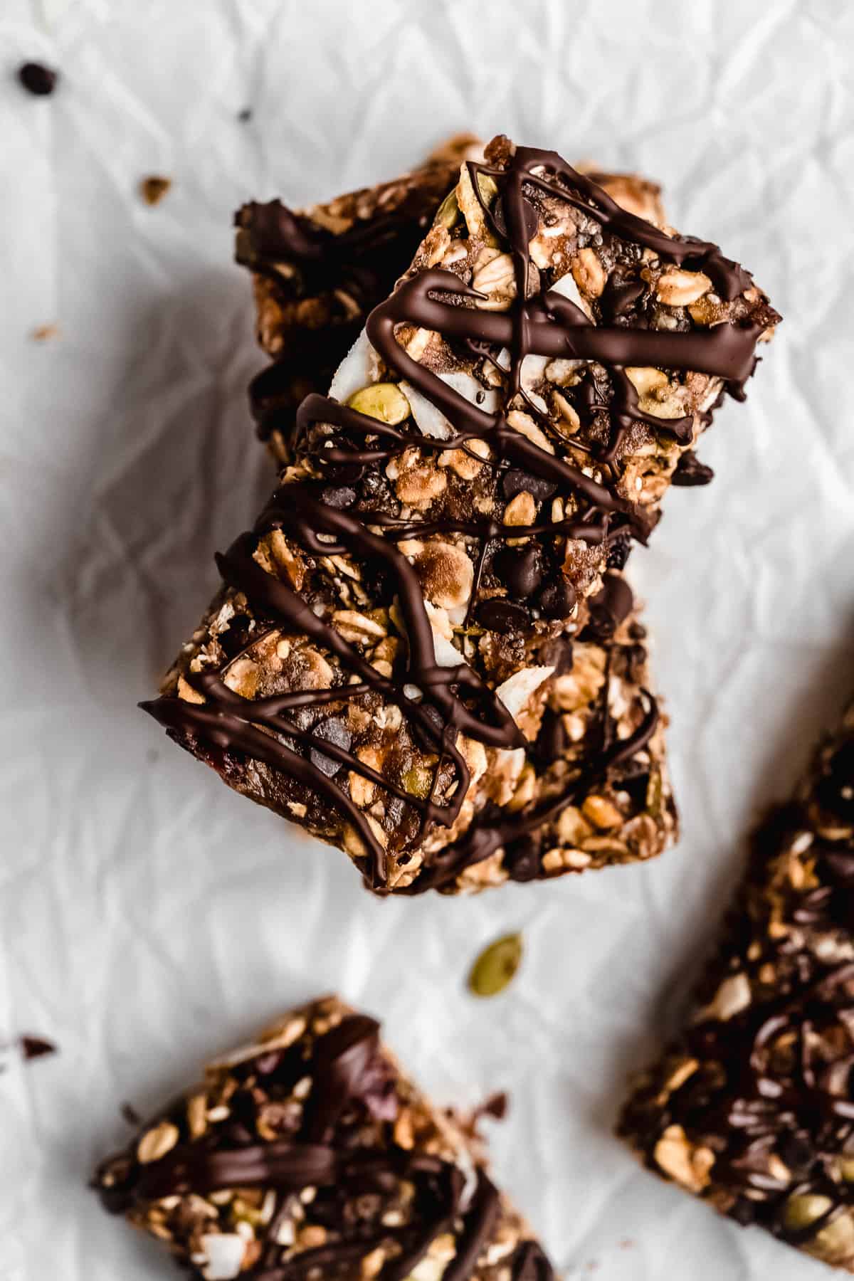 Overhead photo of two Nut-free Chocolate Granola Bars stacked on top of one another on white parchment paper.  