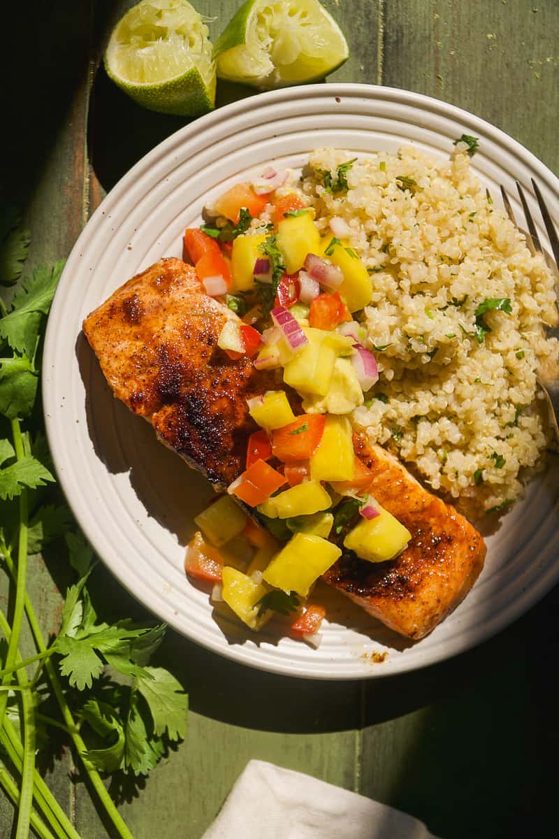 Salmon with mango salsa on a plate with quinoa.
