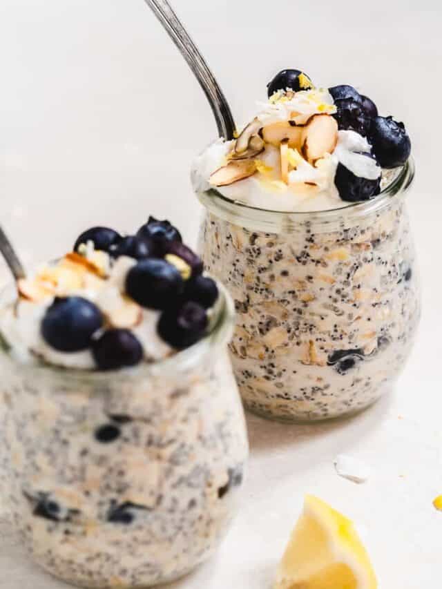 Two jars of lemon poppyseed overnight oat with spoons and blueberries.