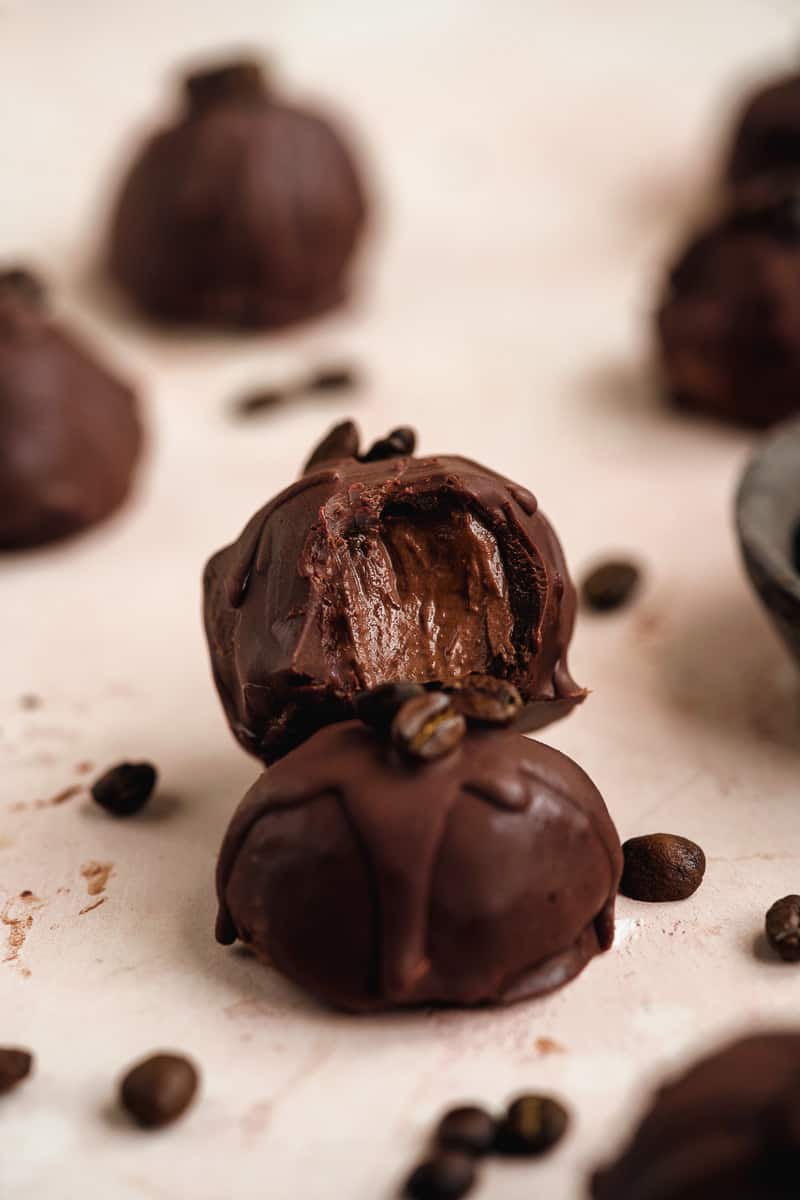 Chocolate espresso truffle with a bite out of one.