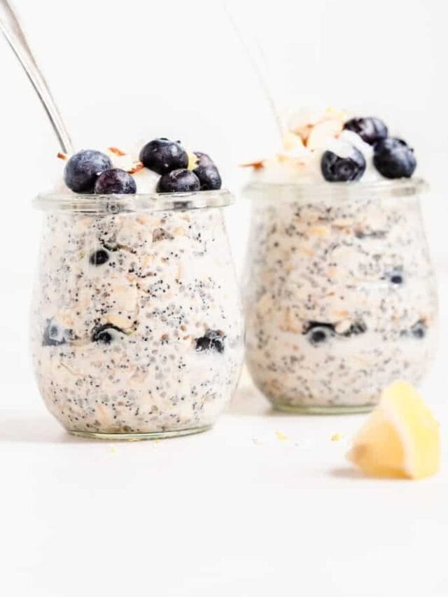 Two jars of lemon poppyseed overnight oat with spoons and blueberries.