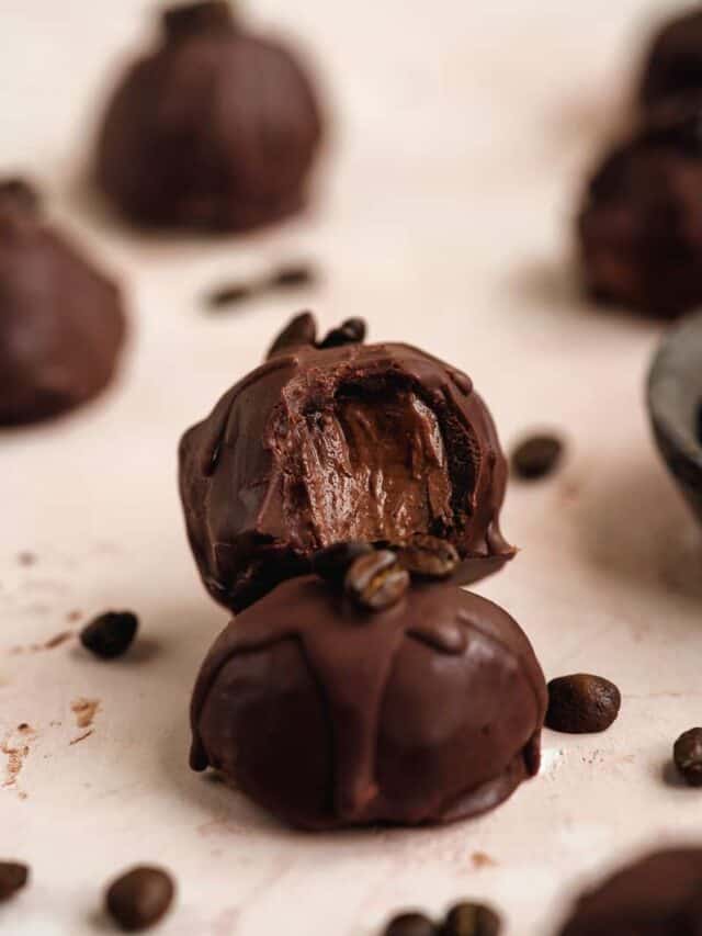 Chocolate espresso truffle with a bite out of one.