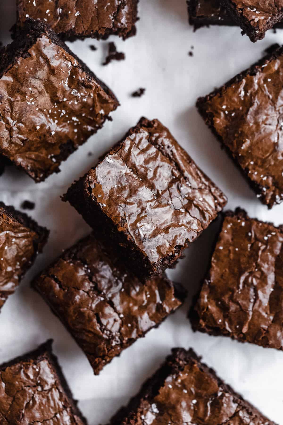 Chocolate almond flour brownies scattered on white parchment paper.