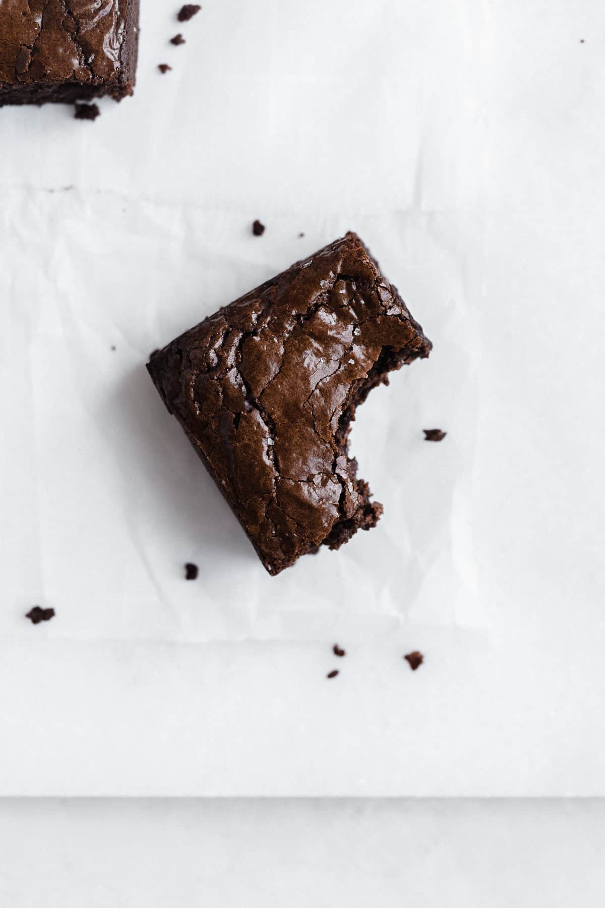 Almond flour brownie with a bite taken out of it on parchment paper.