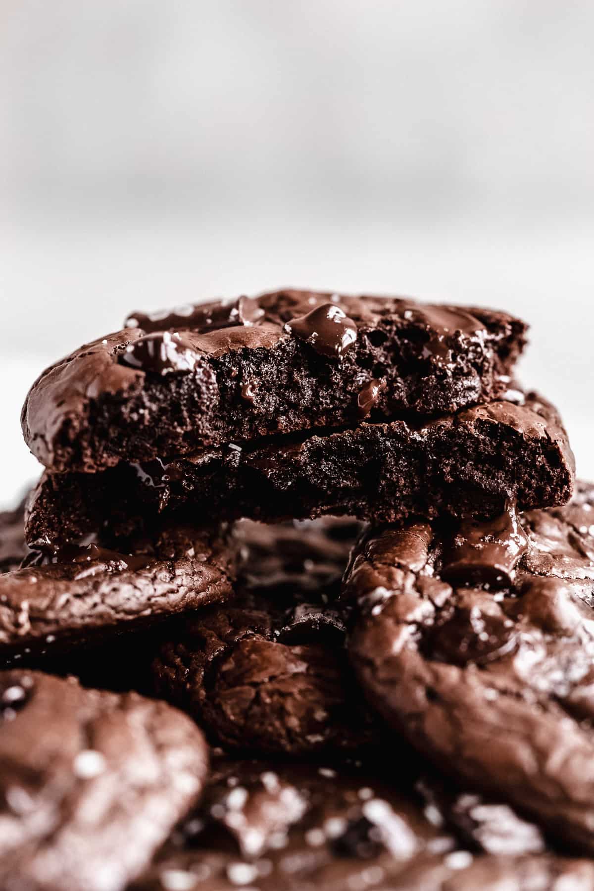 Brownie crinkle cookies stacked in a pile in front of a gray background.