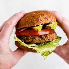 Two hands holding a black bean burger.