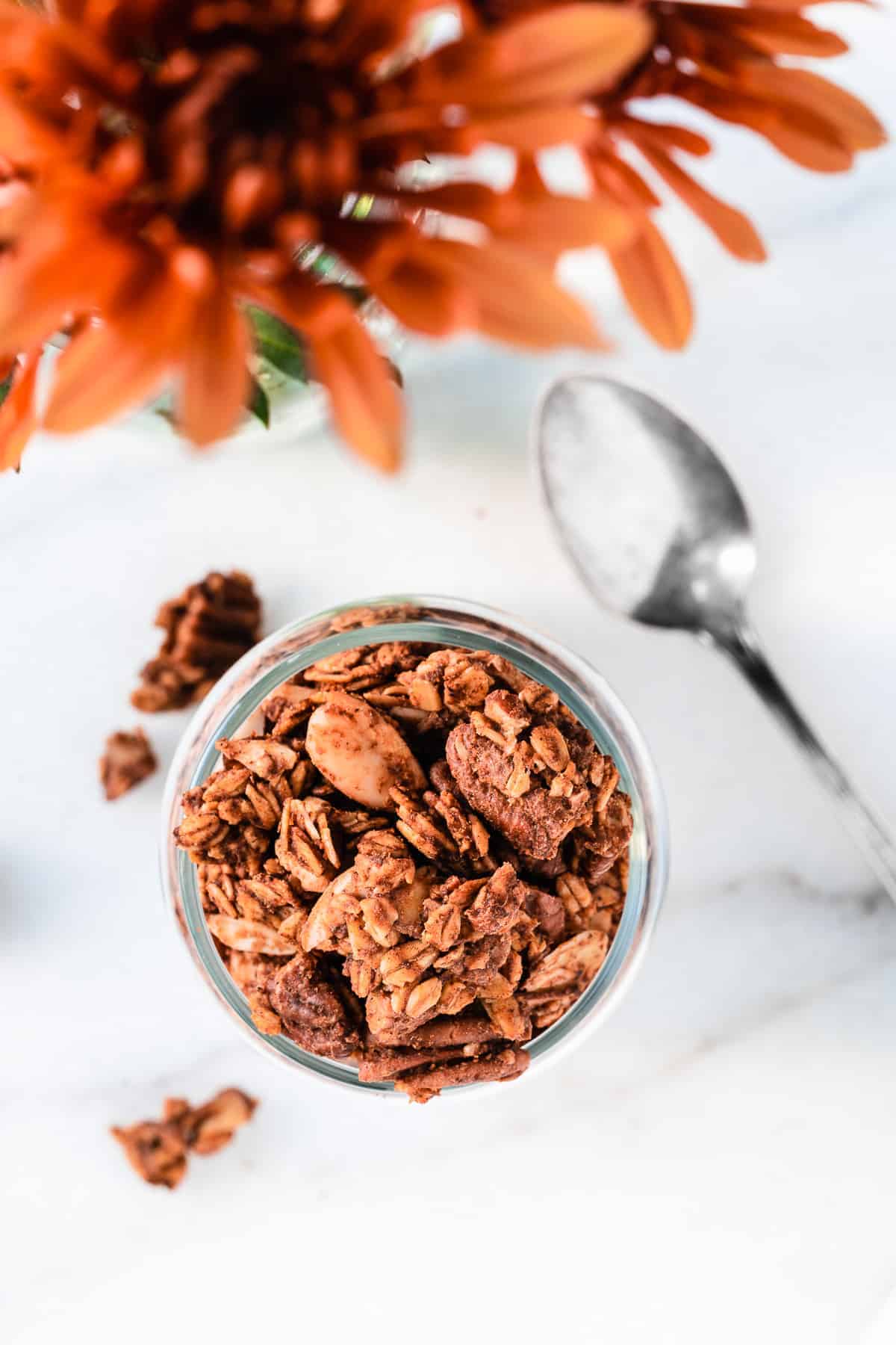 Jar of pumpkin spiced granola from above with orange flowers