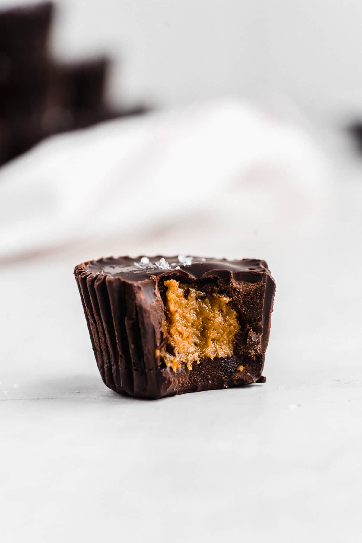 Chocolate pumpkin butter cup on flat surface with bite taken out of it.