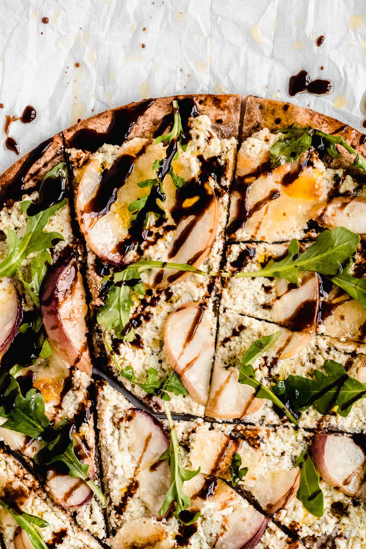 Closeup photo of the toppings on the Crispy White Peach and Ricotta Pesto Flatbread with Balsamic Glaze.  