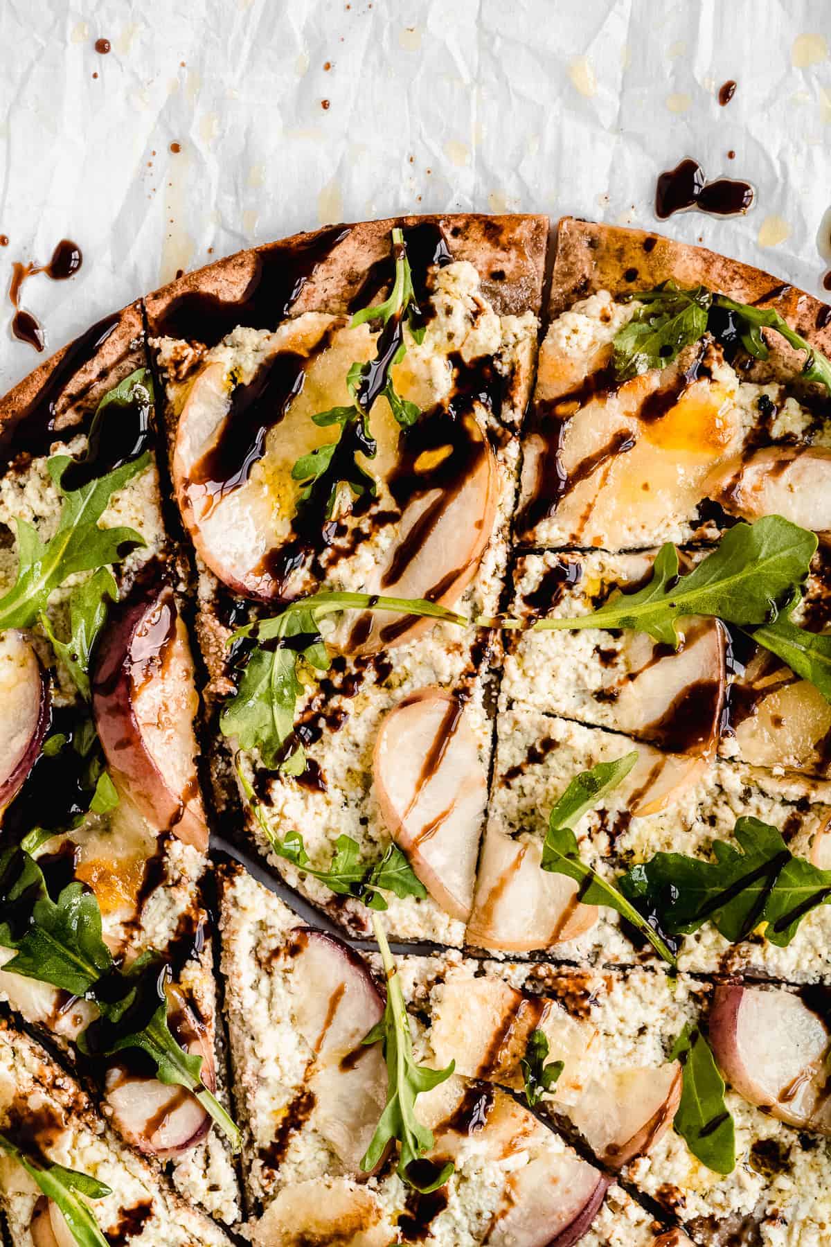 Closeup photo of the toppings on the Crispy White Peach and Ricotta Pesto Flatbread with Balsamic Glaze.