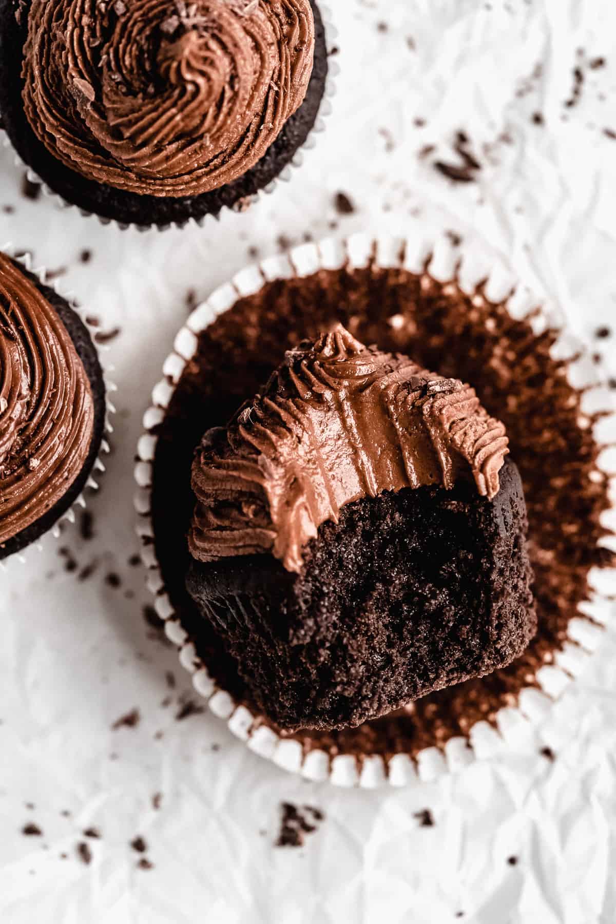 Overhead close up photo of a single Gluten-free Chocolate Cupcake that is sitting on its side with the paper liner pulled away.