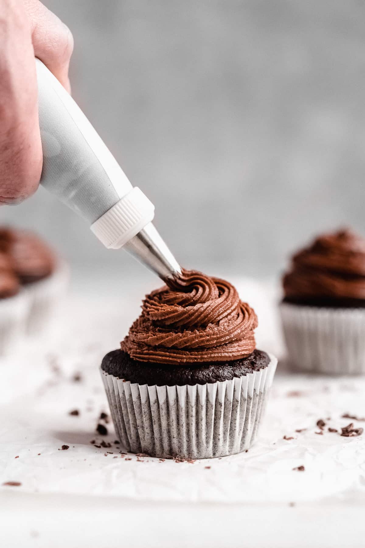 Close up photo of a single cupcake being frosted with an icing tip. 