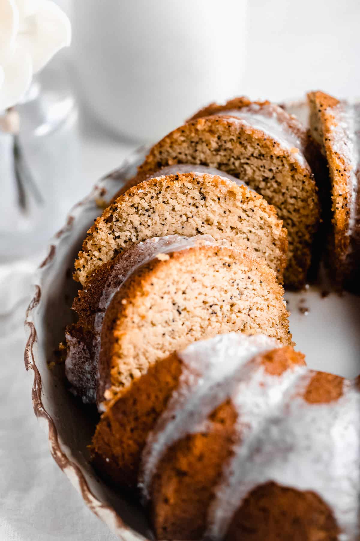 Closeup photo of half of the Citrus-y Gluten Free Lemon Poppy Seed Bundt Cake sliced and sitting on a cake plate.