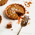 Salted caramel tart with a fork taking a bite out of it.