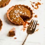 Salted caramel tart with a fork taking a bite out of it.