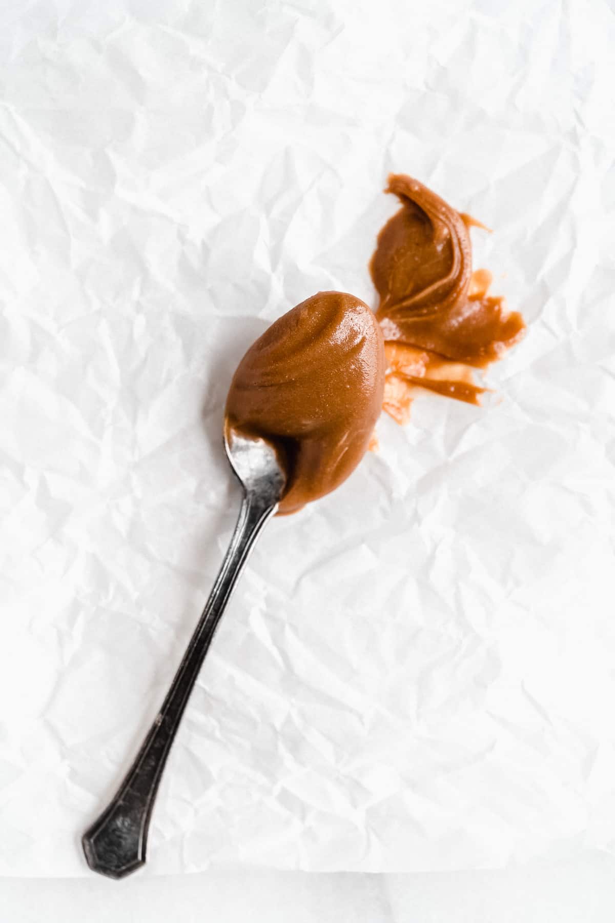 Overhead closeup photo of a silver spoon full of dairy free caramel.