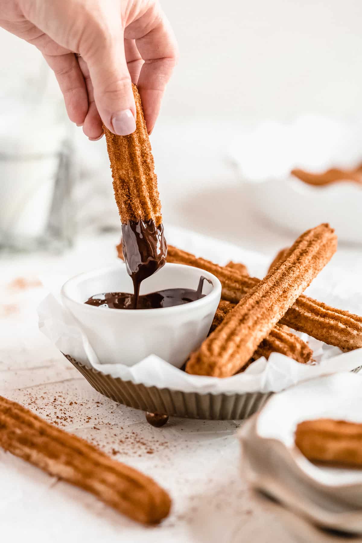 Hand dipping vegan churro into chocolate.