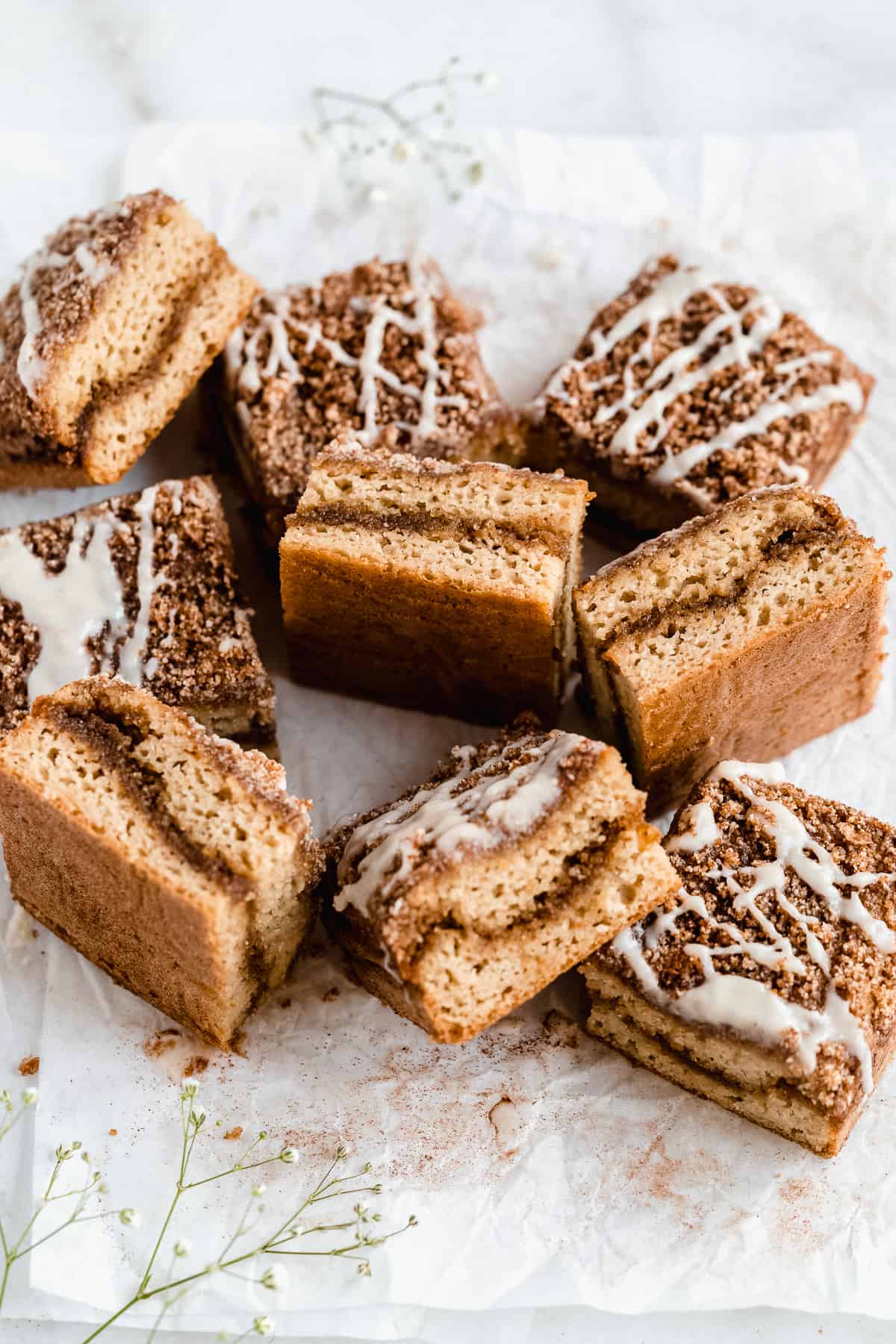 Cinnamon coffee cake cut into slices and scattered on parchment paper.