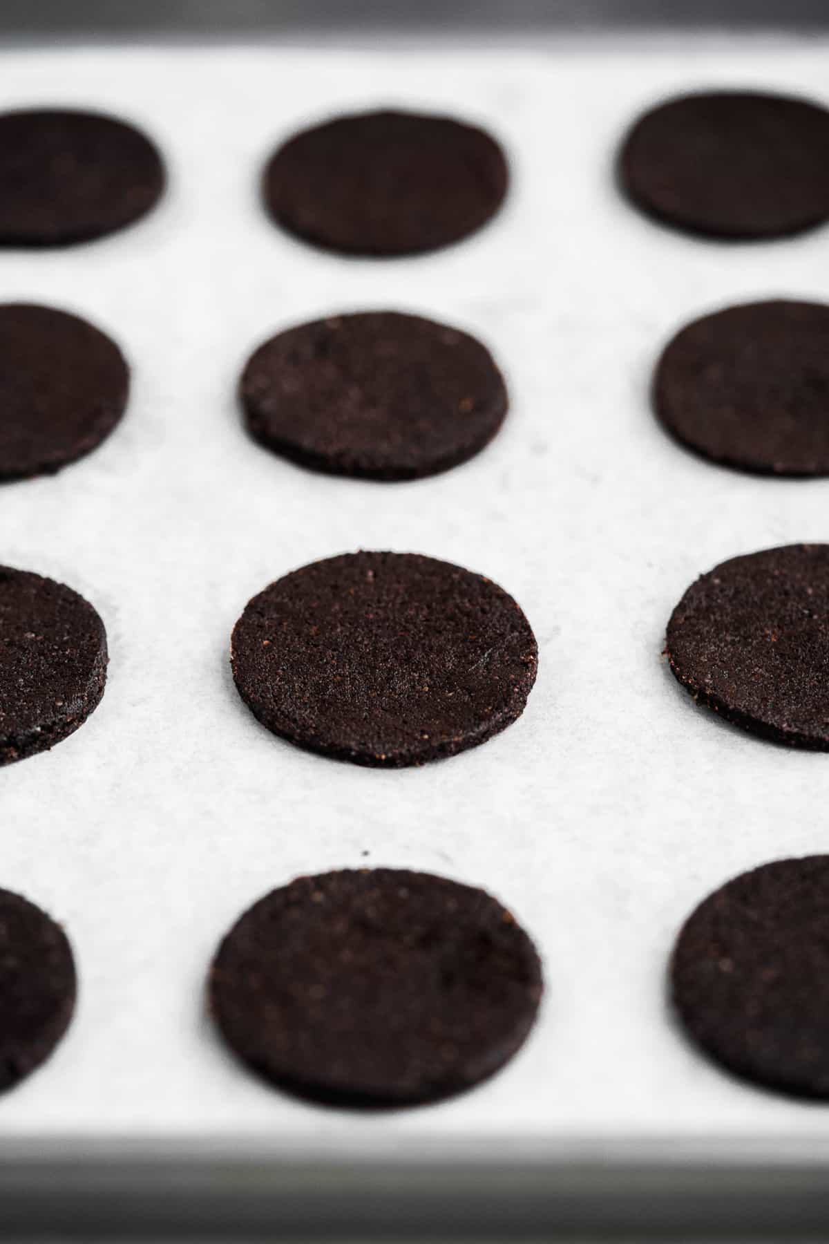 Chocolate circle cookies cut out and on a baking sheet about to be baked.