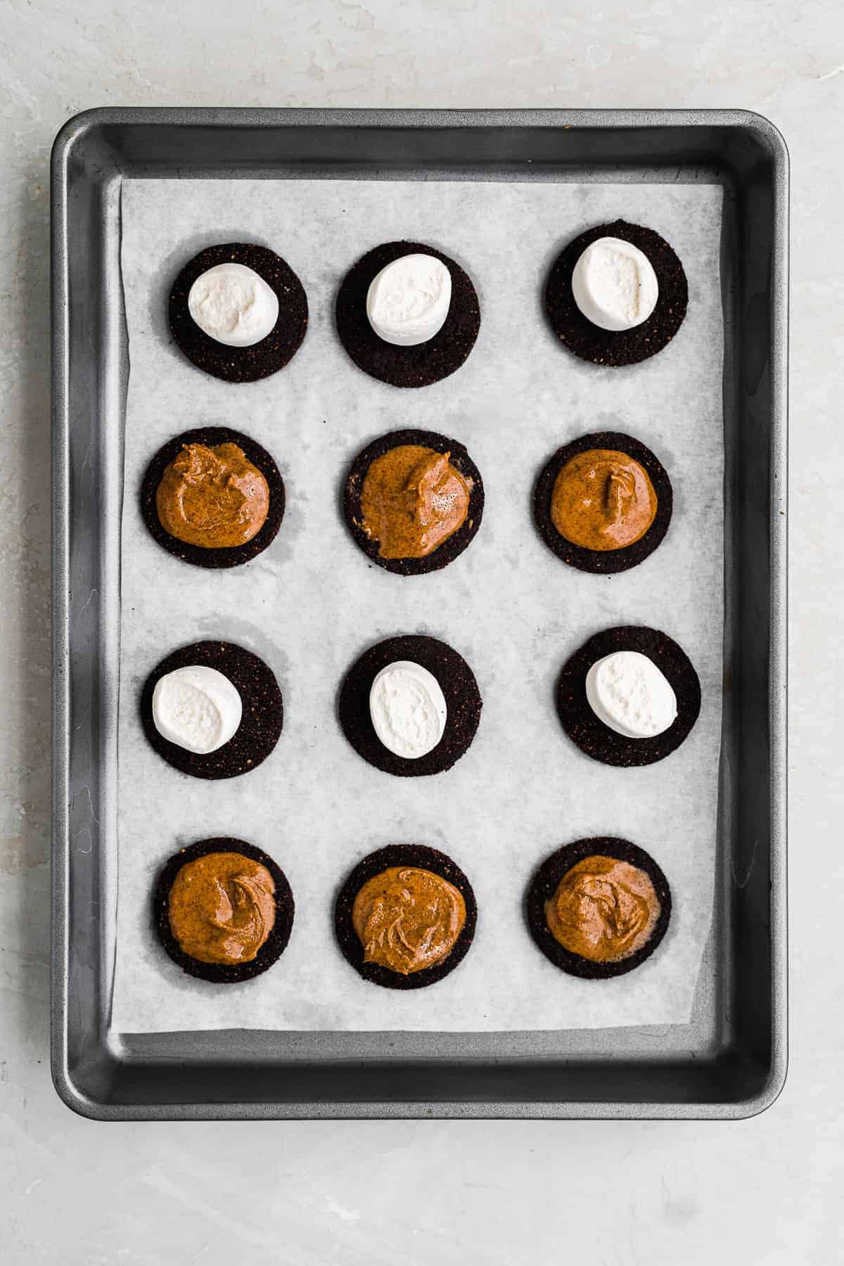 Gluten free oreo cookies with a marshmallow on top of half and almond butter spread on the other half.