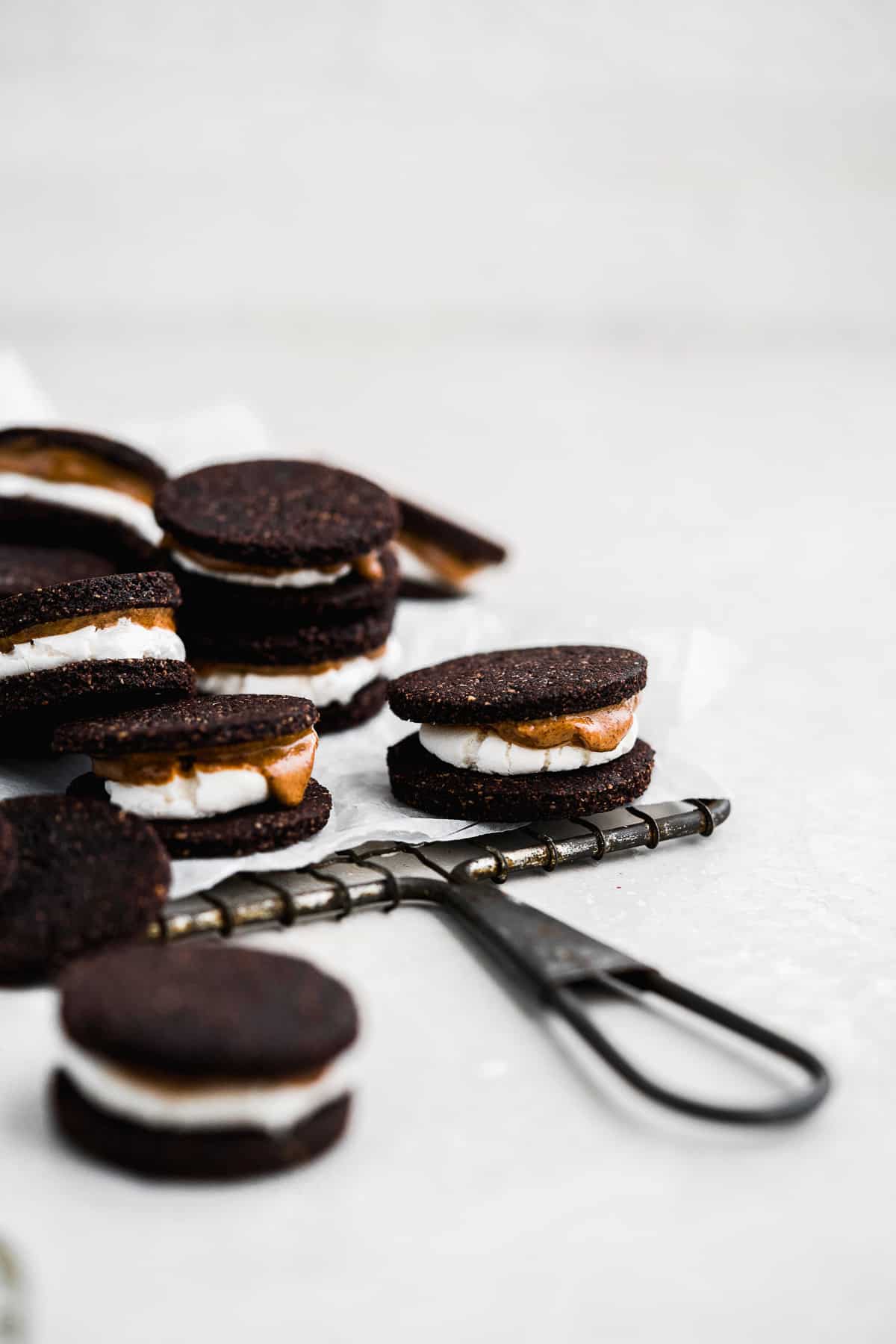 A batch of gluten free Oreo cookies sitting on parchment paper on a metal cooling rack waiting to be enjoyed.  