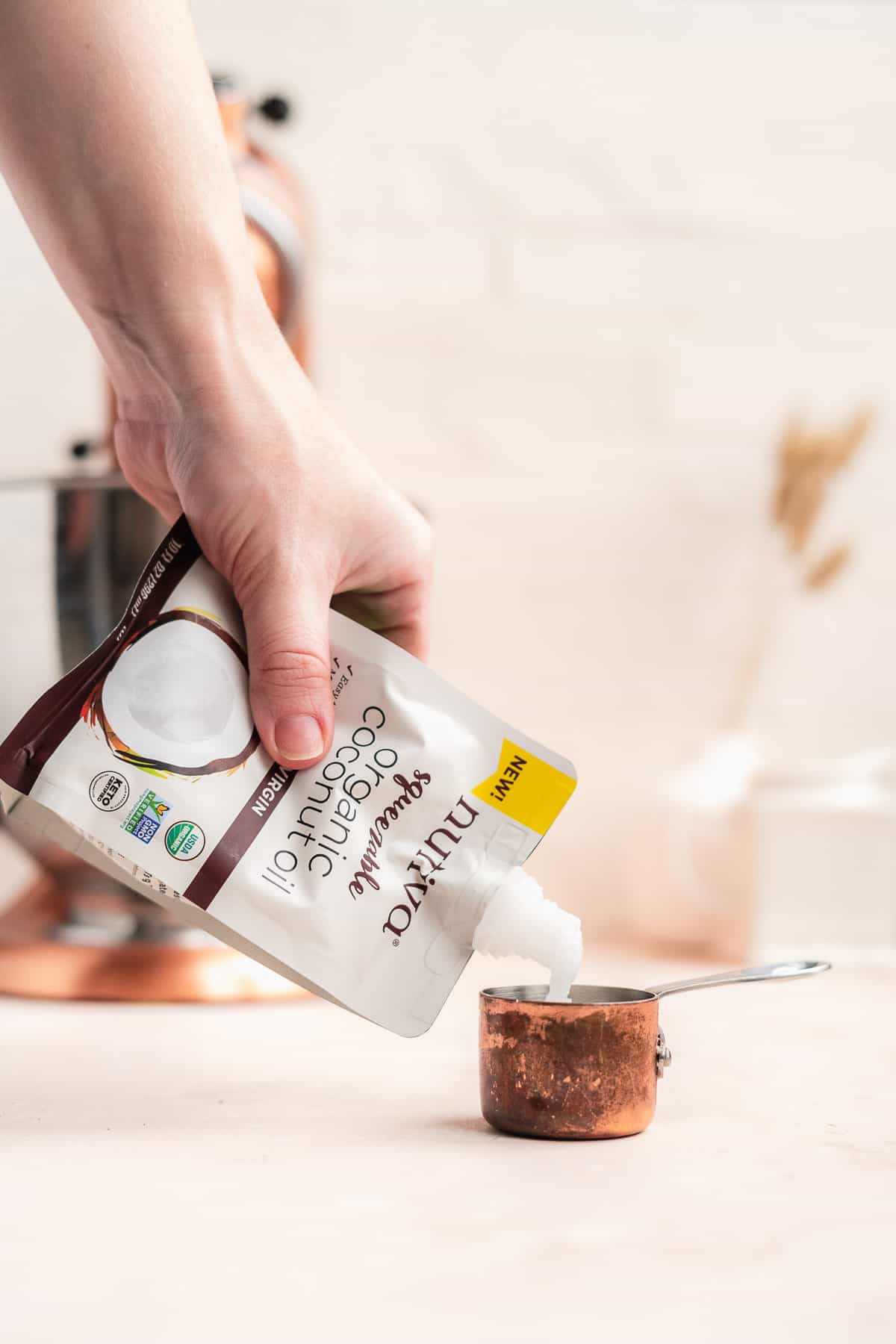 Person squeezing coconut oil in a measuring cup.