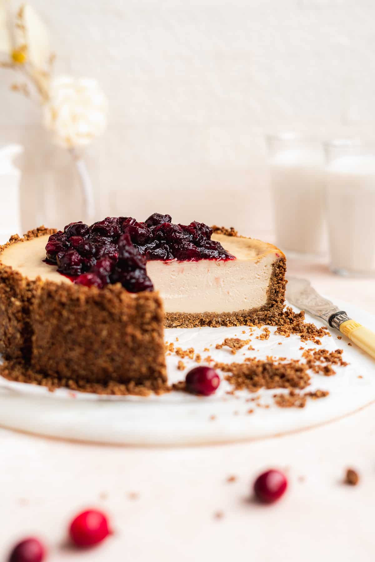 Side photo of Vegan Baked Cranberry Cheesecake with Graham Cracker Crust with a section removed showing the delicious thick cheesecake inside.  