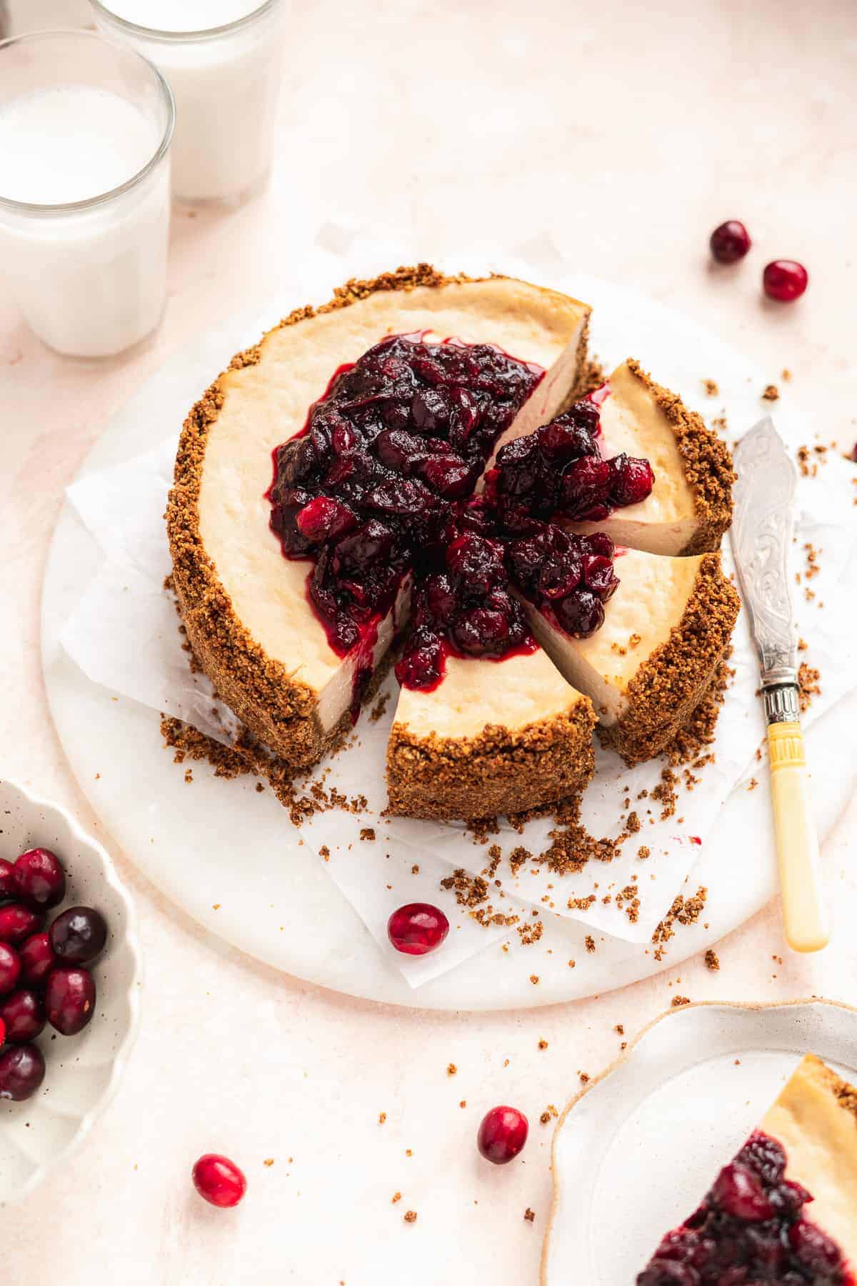 Overhead photo of Vegan Baked Cranberry Cheesecake with Graham Cracker Crust with 3 slices cut sitting on a white marble slab.  