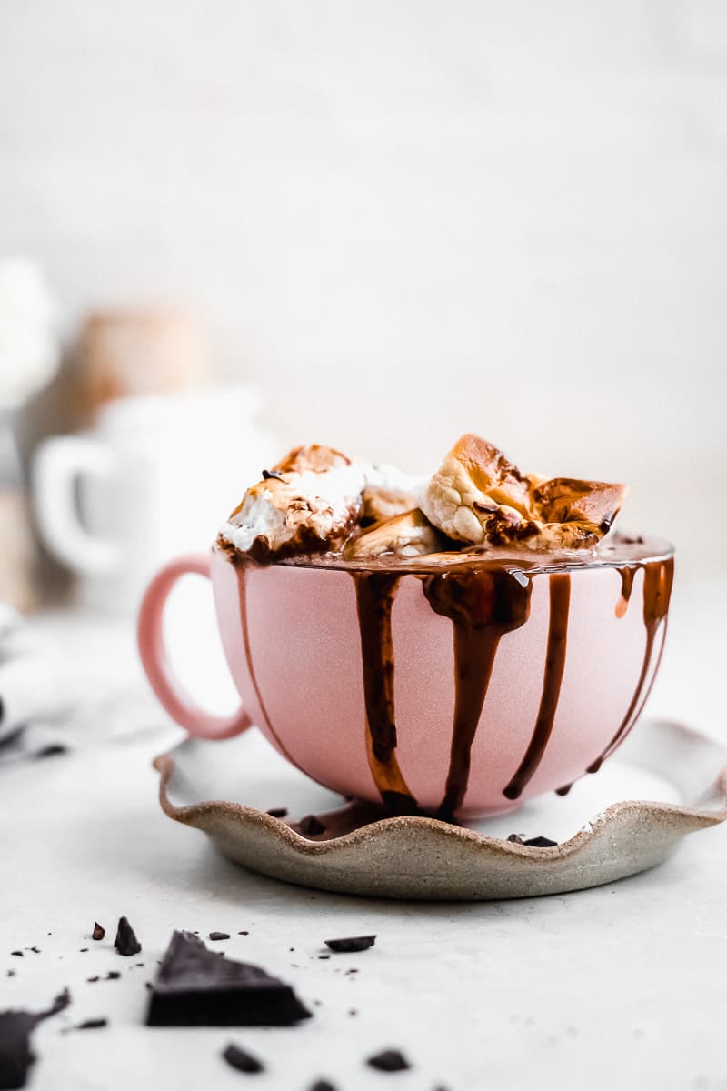 Pink mug with hot chocolate and marshmallows on top.
