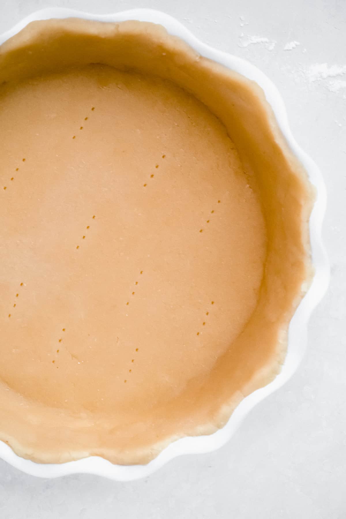 Close up photo of the completed formed pie crust with fork pricks made in the bottom of the unbaked crust.  
