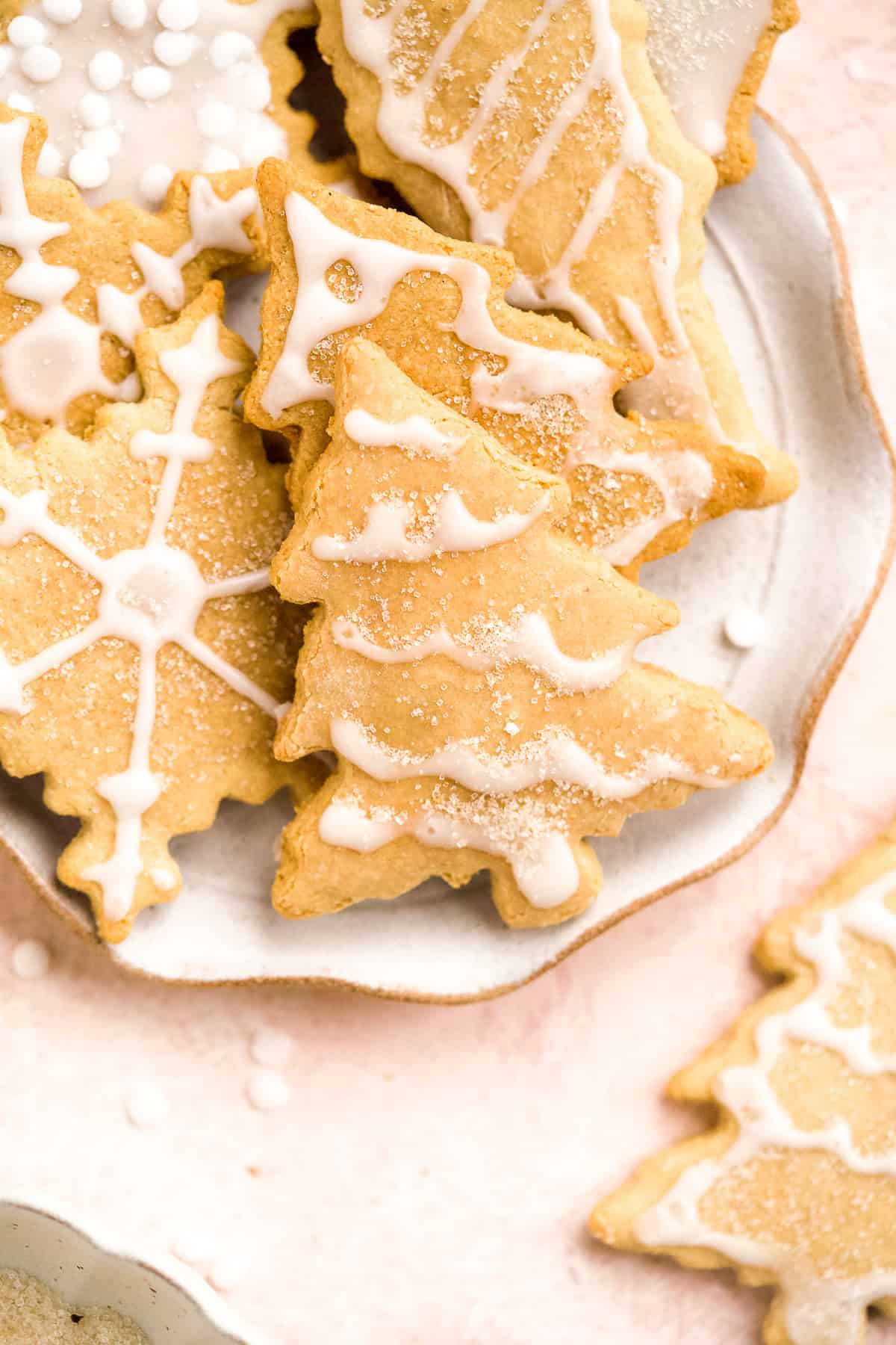 Close up overhead photo of snowflake and Christmas tree shaped Soft and Crispy Gluten-free Sugar Cookies on a scalloped plate.  