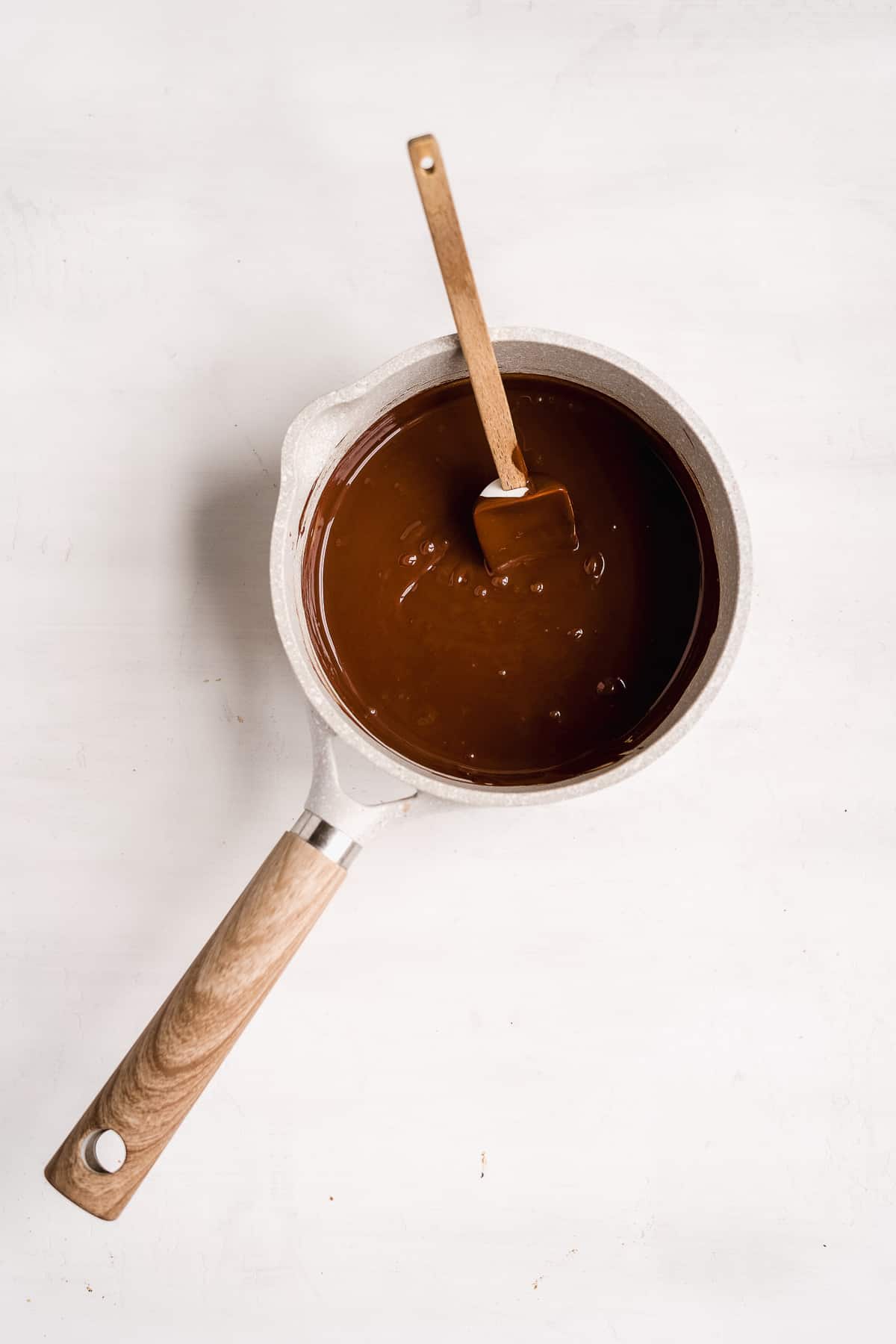 An overhead photo during the process of making the Chocolate Toasted Hazelnut Cheesecake to show the melted chocolate in a saucepan.  