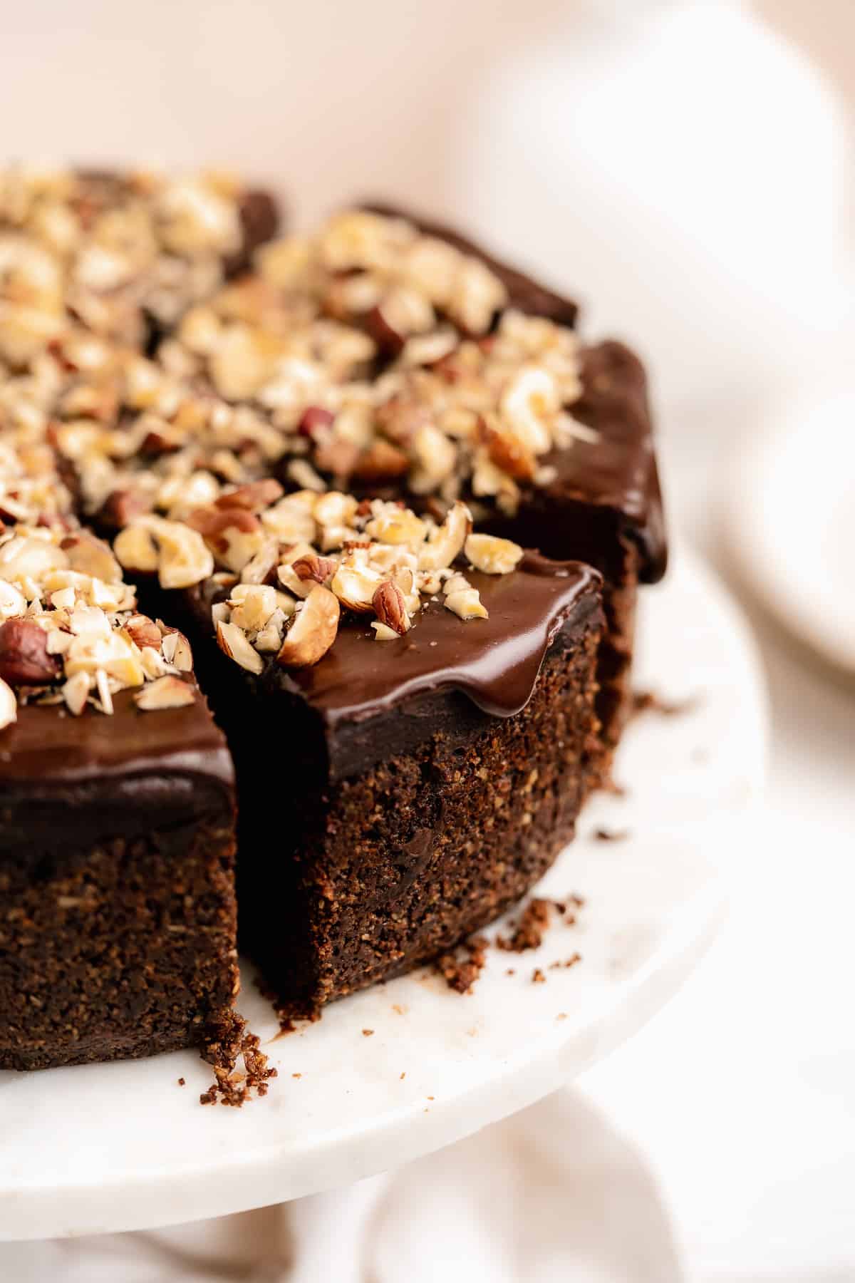 Close up view of a sliced Chocolate Toasted Hazelnut Cheesecake to detail the thickness of the base and the yummy chocolate topping with hazelnut pieces sprinkled on top.  