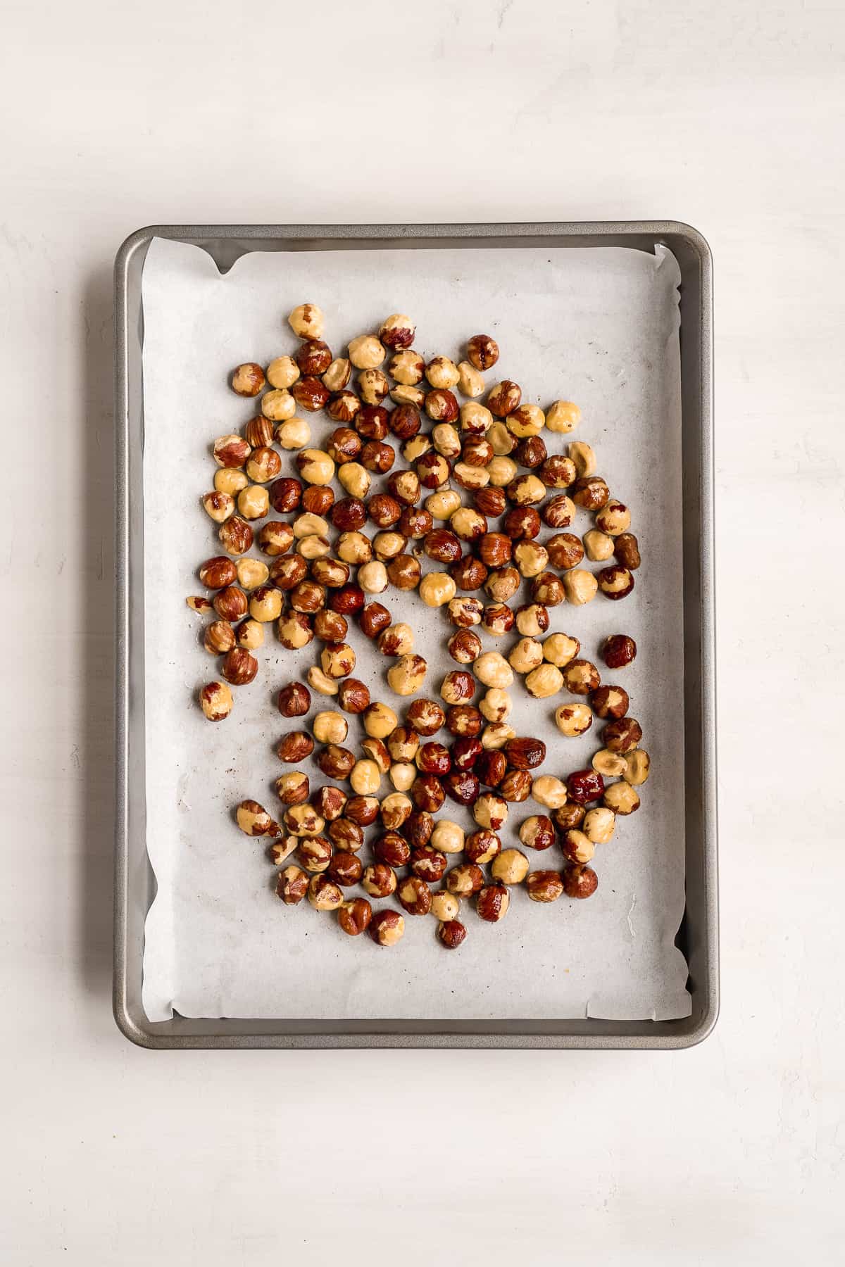 Hazelnuts scattered on a baking pan.