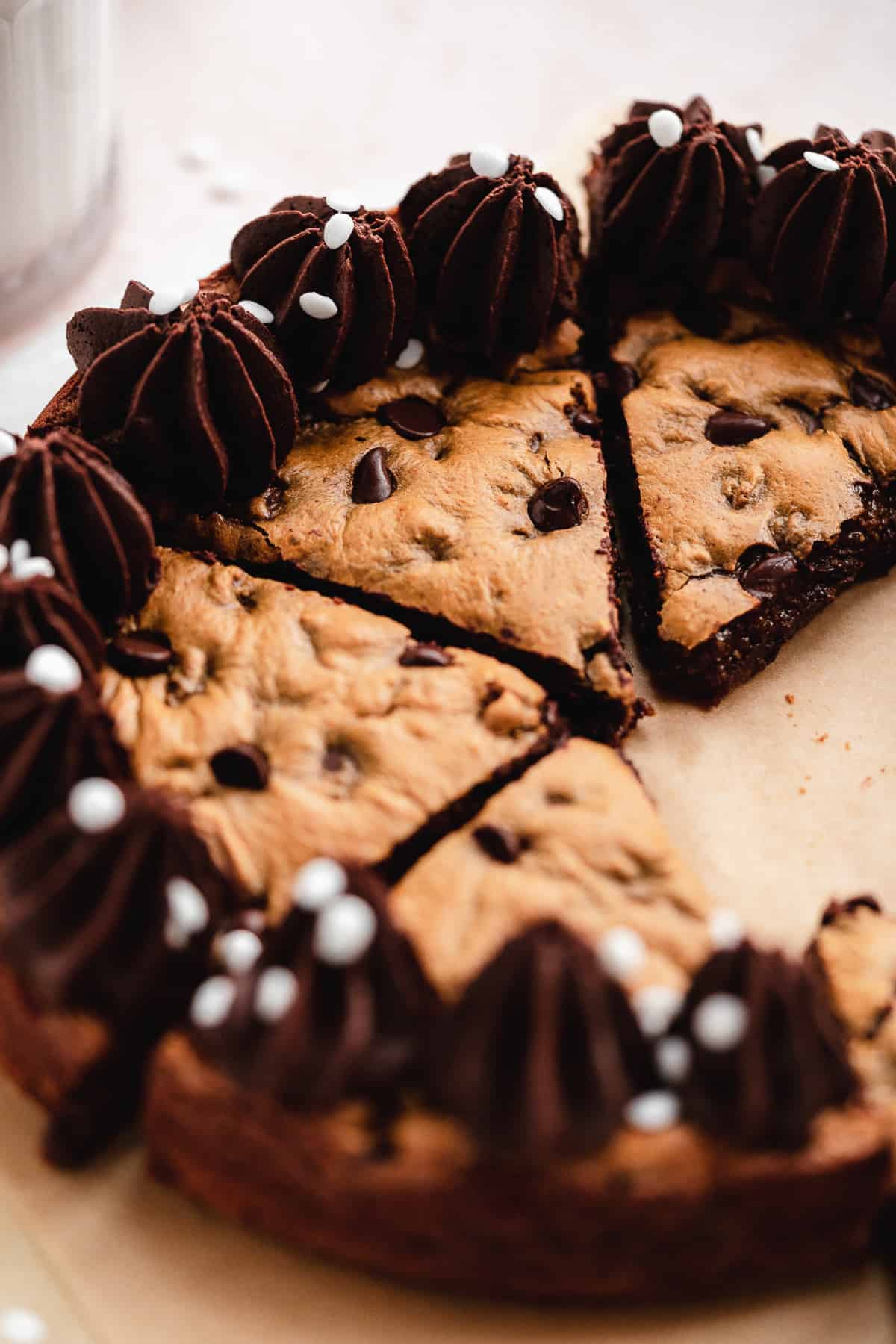 Closeup photo of chocolate chip cookie cake cut into triangular pieces showing delicious inside filling.