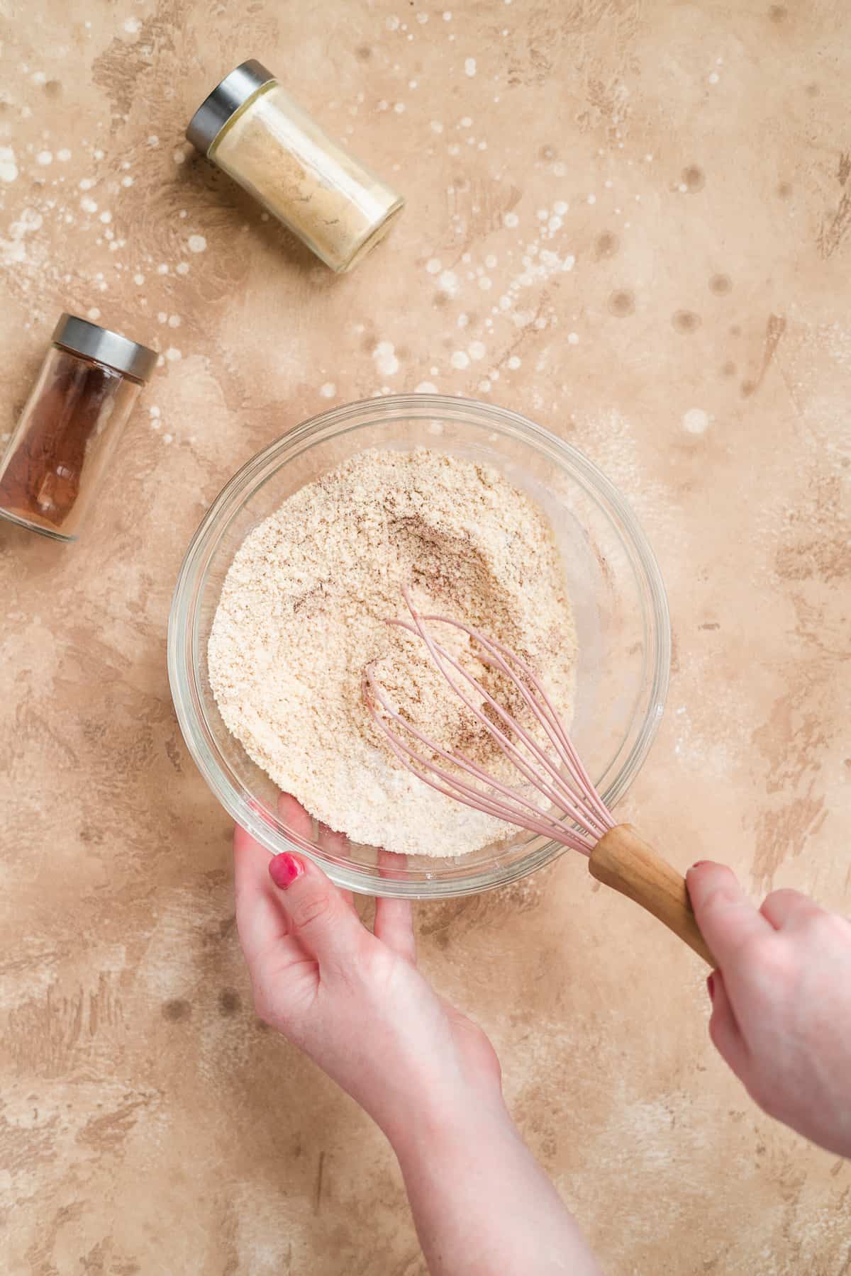 Person whisking dry ingredients in a bowl for ginger snaps.