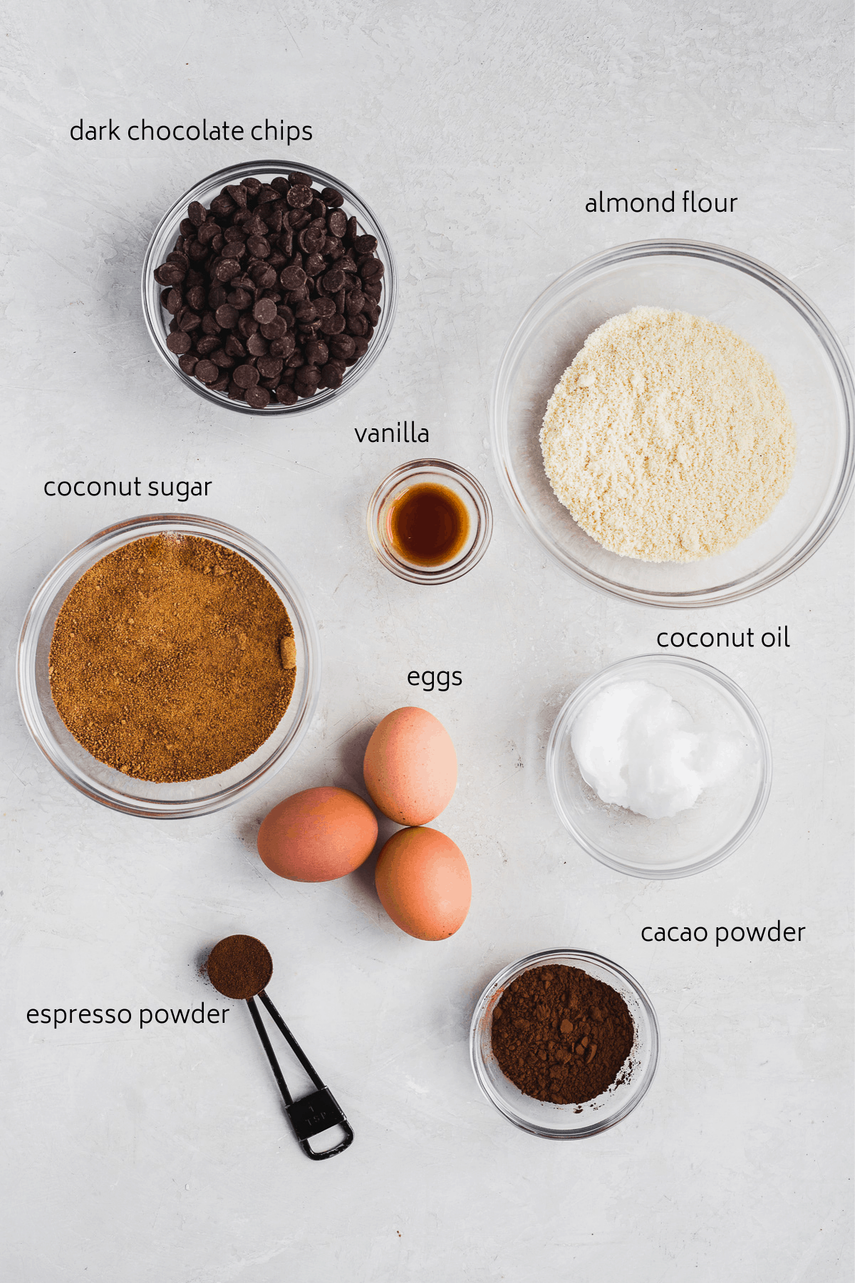 Brownie ingredients on a white surface with labels in black.