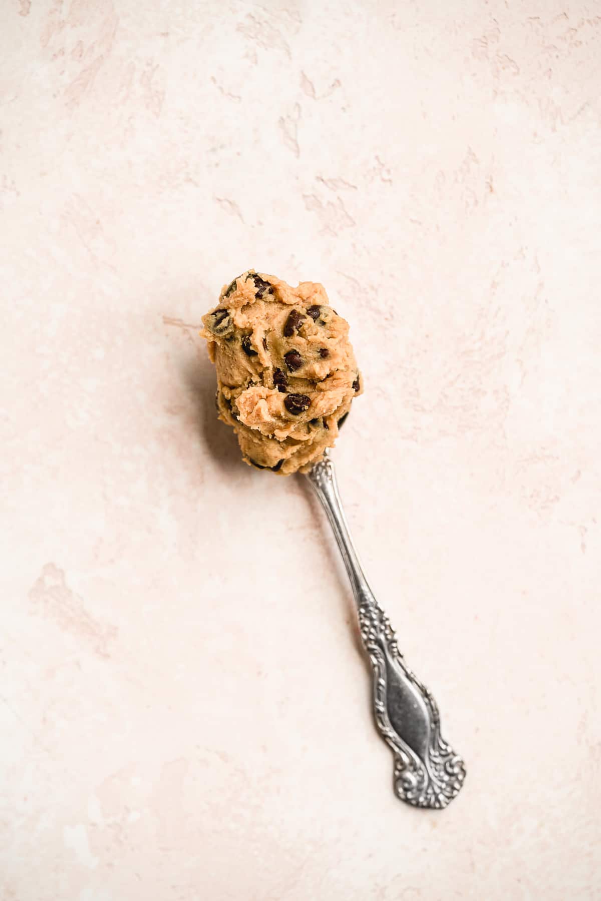 A silver spoon filled with a giant dollop of delicious edible chocolate chip cookie dough.  