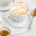 salted caramel oat milk latte in a white coffee cup on a white surface