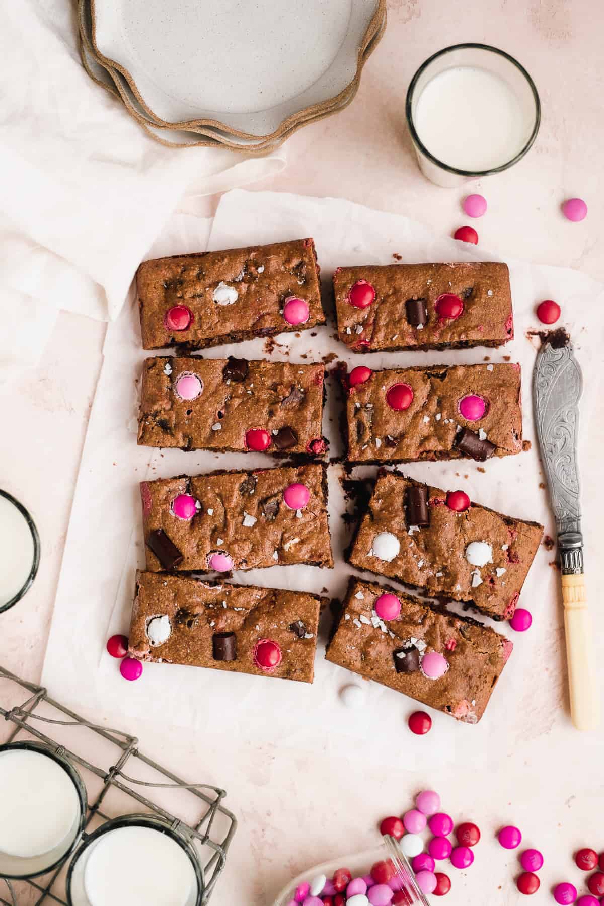 Cookie bars scattered on white parchment paper with Valentine's Day M&Ms on top.