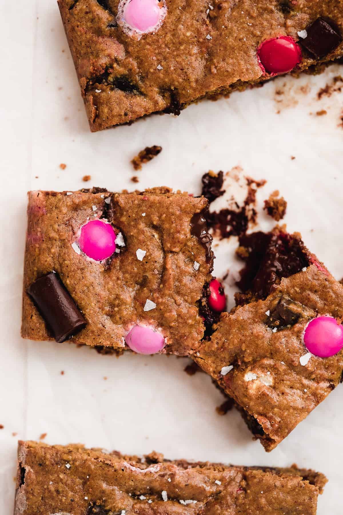 Cookie bar pulled apart with chocolate in the middle and pink and red M&Ms on top.